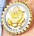 A small pin held onto a necklace with a Congressional seal on it