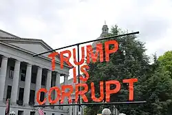 A sign reading "TRUMP IS CORRUPT"
