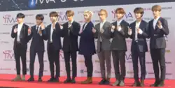 Members of Stray Kids wearing suits on a red carpet.