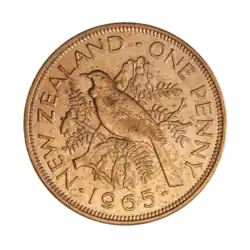 A penny featuring a tūī bird perched atop the branch of a kōwhai tree, surrounded by flowers and leaves, and encircled by the text "NEW ZEALAND - ONE PENNY - 1965"