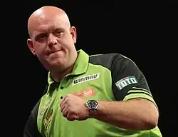 Michael van Gerwen celebrates with a clenched fist during a darts match.
