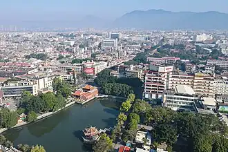 A view from above at a city, including a pond with a pavilion