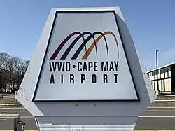 Large sign reading "WWD Cape May Airport" with a logo consisting of four colorful arches which partially overlap