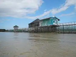 A bamboo and net structure supporting small buildings in a river