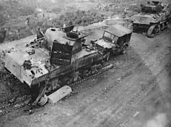 Two damaged tanks with their tracks visibly destroyed and a damaged Willy's Jeep displaying the 6th Armoured triangular flash