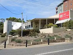 a building with the name ABC South West and a satellite dish on the side. There is a retaining wall and a small garden in front.