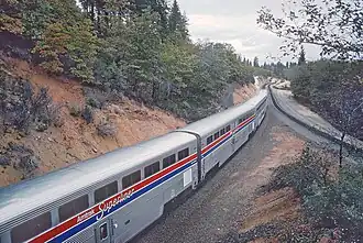 Silver railcars next to a hill