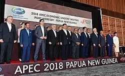 Leaders of APEC countries standing in two rows on a stage