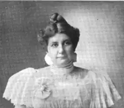 B&W portrait photo of a middle-aged woman wearing an over-sized white blouse, with her hair in an up-do