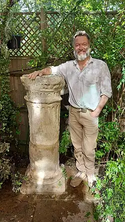 Photograph of Alex Wenham with a stone column