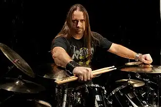 Alfonso Pinzón posing behind a drum kit, looking directly at camera