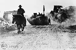 B&W photo of a man on a horse with a tank behind him
