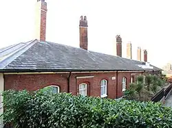 A terrace of red brick single story dwellings.