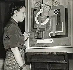Irene Rice Pereira smoking a cigarette while looking at a painting