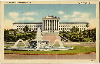 A color postcard showing a large building with classical Greek columns in the background and a fountain in the foreground