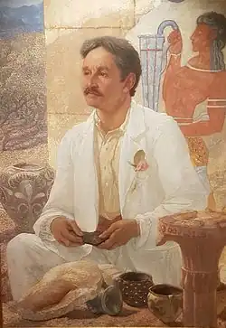 Painting of a man, holding something (a potsherd or Linear B tablet) in his hands, seated looking into the distance: a Minoan fresco is visible behind him.