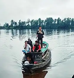 Four people on a small boat floating on a still body of water