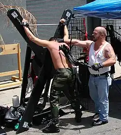 A man is flogged with a multi-tailed whip as he is tied to an X-cross