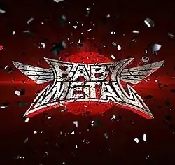The Babymetal logo, set over a red circle on a darker red background, surrounded by an explosion of silver particles