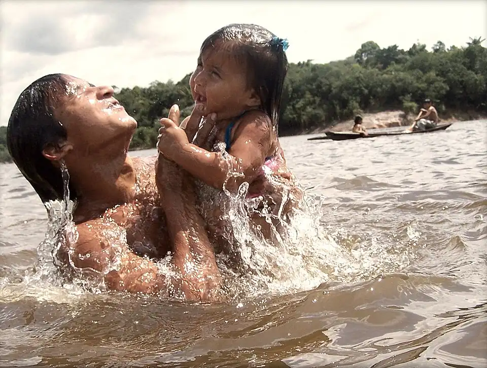 An adult and a child are seen bathing on a river