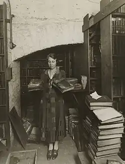Female employee holding damaged books in the basement, black-and-white