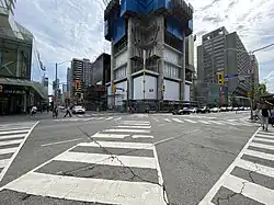 The intersection of Yonge Street and Bloor Street, two of Toronto's most prominent thoroughfares. Zebra markings on the road outline a scramble crossing.