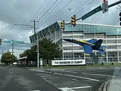 A photograph of the Museum of Flight, a large glass museum hall, taken from a street intersection in Tukwila