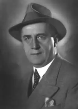A clean-shaven man in a suit and a short-brimmed hat