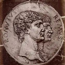 Ceramic medallion featuring the busts of two men facing right, identified as Romulus and Remus.