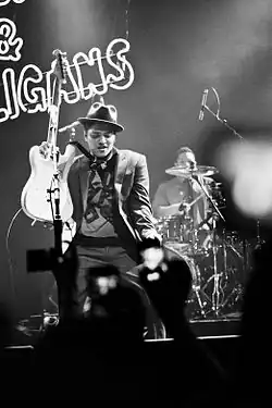 A black and white photograph of Bruno Mars performing with his band at a concert
