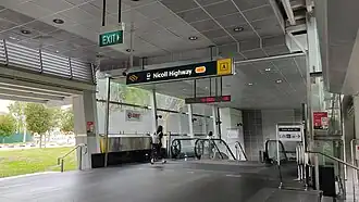 Photograph of the station entrance with the sign indicating the station name and alphanumeric code (CC5). The entrance is connected to a sheltered linkway.