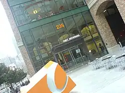 A building with a glass and brick facade. Tall buildings are visible in the background.