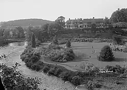 A large, mock-Tudor mansion, with parkland and a long river beside it