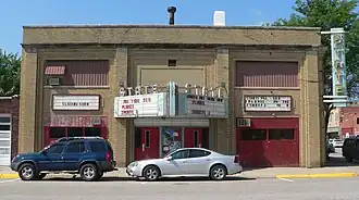 Two-story brick building; triangular marquee projecting from front; vertical "State" sign projecting from corner