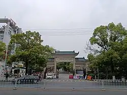 The entrance of Changsha Social Work College in Changsha, Hunan, China. The traditionally ornate styled gate is framed by leafy trees either side