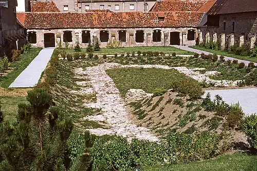 Colour photograph of an excavated courtyard surrounded by a cloister, of which all the bays have disappeared.