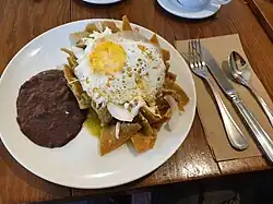Chilaquiles may be served with minimal salsa applied at the last minute to preserve the crispiness of the tortilla chips