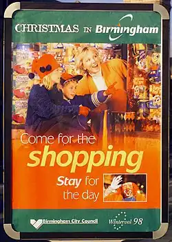 "Poster with the headline 'Christmas in Birmingham', then a picture of a mother and children, looking at toys, with the words 'Come for the shopping, stay for the day'. Below that, in smaller type, the Birmingham City Council and Winterval 1998 logos."