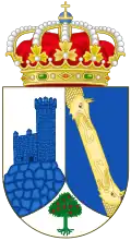 A shield with a crown on top. The shield is divided in three parts, having the left part an image of the watchtower of Torrelodones, colored blue with a white background, the right side has two dragon looking yellow creatures facing each other over a blue background, and on the bottom part is a small green three with red fruits over a white background