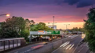 View of both carriageways of the ring road and junction 9 slip roads, with overhead signage, taken at dusk