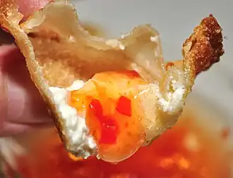 Inside, showing the crisp shell, white filling, and golden dipping sauce.