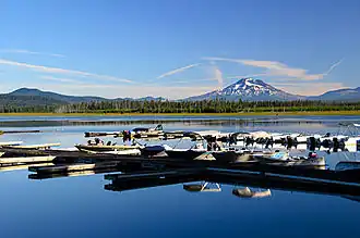 Boat dock with boats with calm water on a sunny day. Mount Bachelor is in the distnace.