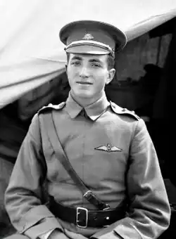 Half-length outdoor portrait of young man in military uniform and peaked cap, with pilot's wings on left breast pocket