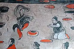 A male dancer wearing a black jiaolingpao over a pair of red trousers, Dahuting tomb, Eastern Han dynasty