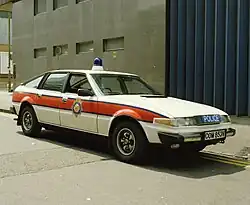 A large white car with a red stripe on the side parked in front of a garage shutter door