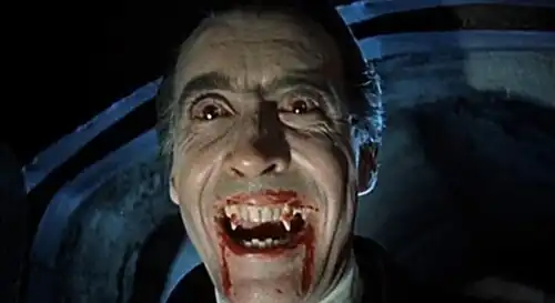 Man with bloodshot eyes and a wide-mouthed and bloody smile, showing exposed fangs