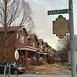 Series of brick duplexes on a residential street. A street sign in the foreground indicates the “Garden District” of the Southwest Garden neighborhood.