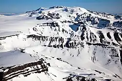 A flat-topped, snow-covered mountain with snow-covered ridges in the foreground