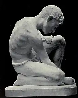A marble sculpture of a boy playing marbles