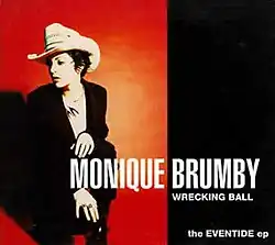 The left half depicts the artist on red background. She wears a cowboy hat and a dark suit. She is crouched down on one knee with her head turned to her right. Her name is in large print near the bottom of the cover. The right half has a black background with white print. Below her name is the lead track, "Wrecking Ball", below that is the title, the Eventide ep.